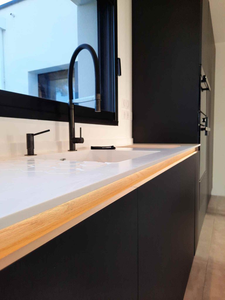 Cuisine contemporaine sur mesure en Corian et chêne noir avec colonnes intégrées à Metz